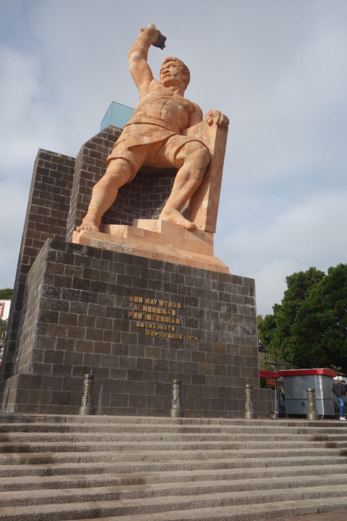 An 80 ft tall statue shows El Pípila, bare-chested, with one arm leaning on a rock slab and the other holding a torch high above his head. He literally opened the door for the insurgents in one of their first major victories toward independence.